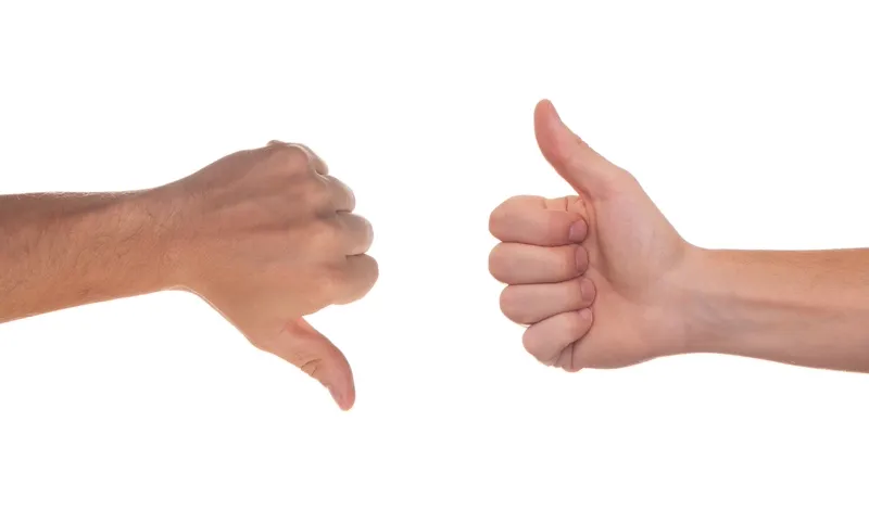 Duas mãos fazendo gestos de positivo e negativo, representando a comparação entre consignado e cartão consignado