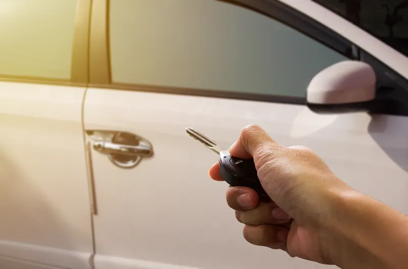 Mão segurando um controle de chave para destravar a porta de um carro