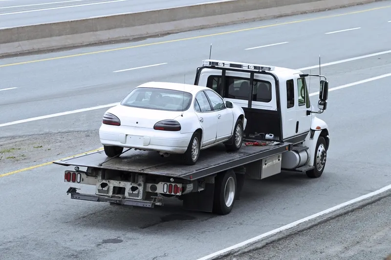 Guincho reboque carregando um carro na estrada, representando o risco de apreensão do veículo por falta de pagamento