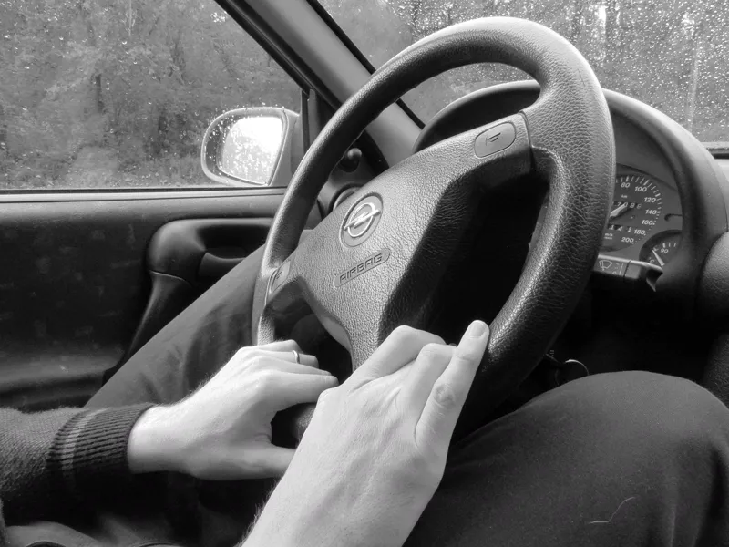 Mãos de um motorista no volante de um carro