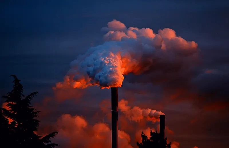 Chaminé industrial emitindo fumaça ao entardecer